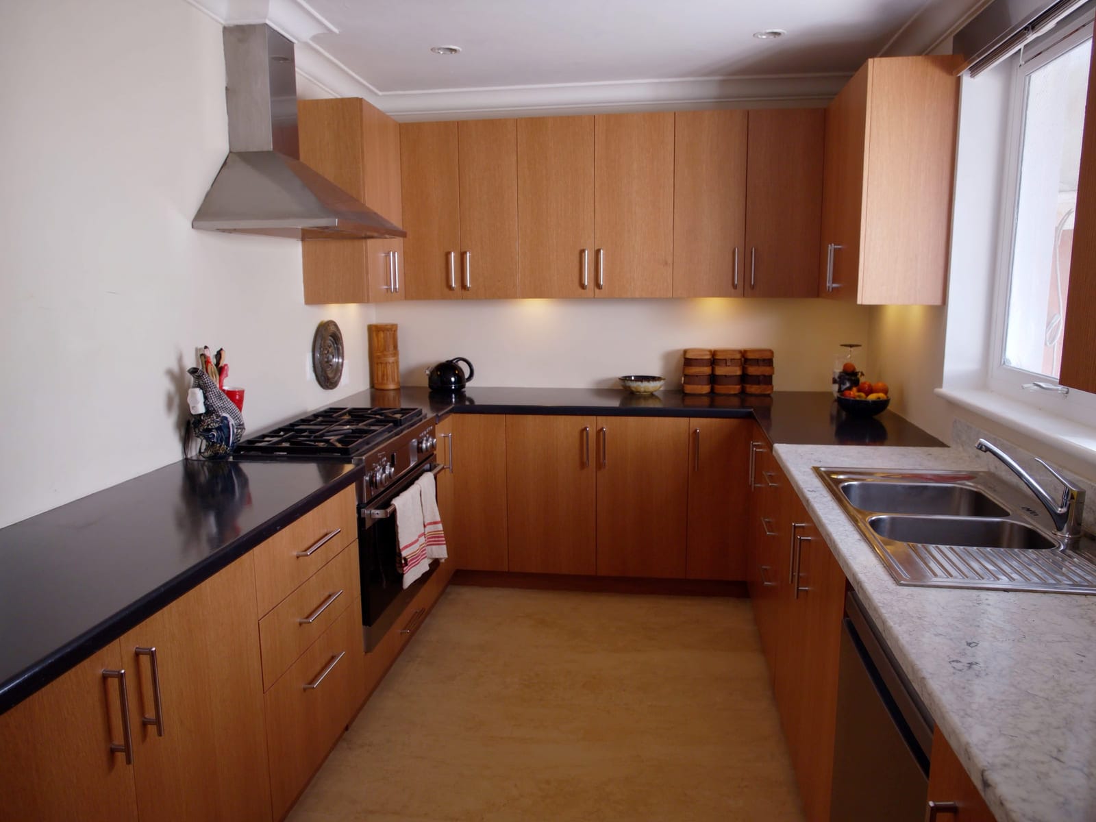 A modern fitted kitchen with cabinet fronts in warm oak woodgrain melamine, a dark laminate worktop and a stainless steel sink. Illustrative concept visual, not a real photograph.